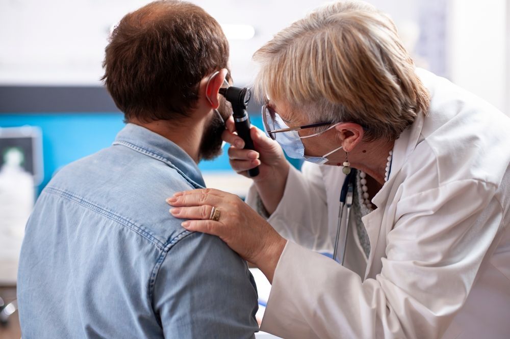 Doctor Examining a Patient’s Ear With an Otoscope in a Clinic Office — HealthHub Taree in Taree, NSW