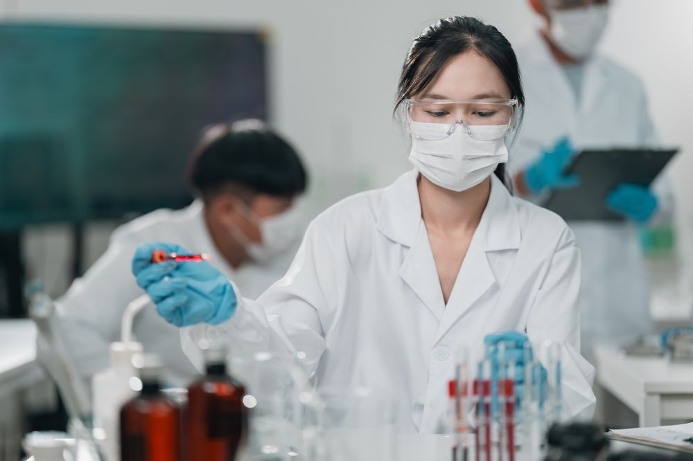 Scientist in Lab Coat and Mask Working With Test Tubes in a Laboratory — HealthHub Taree in Taree, NSW