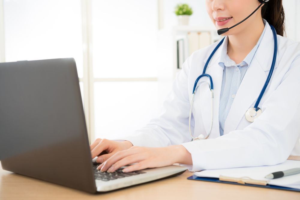 Doctor Wearing Headset Typing on Laptop at a Desk in a Bright Office — HealthHub Taree in Taree, NSW