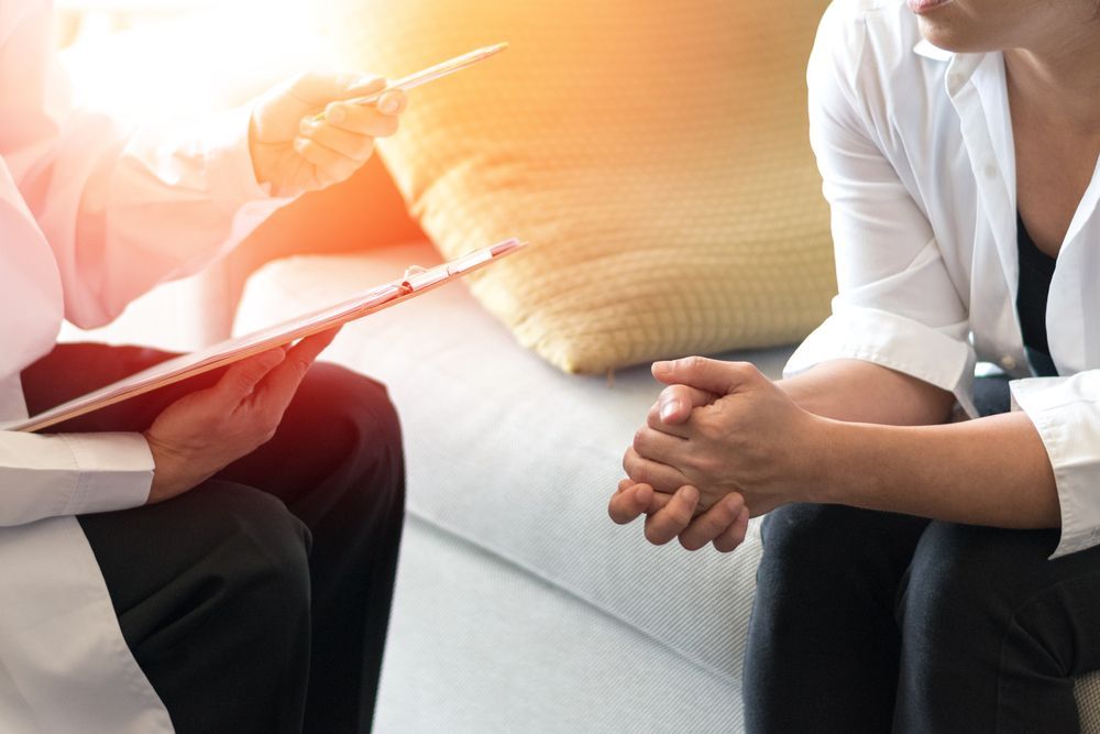 Two People Talking on a White Couch, One Holding a Clipboard — HealthHub Taree in Taree, NSW