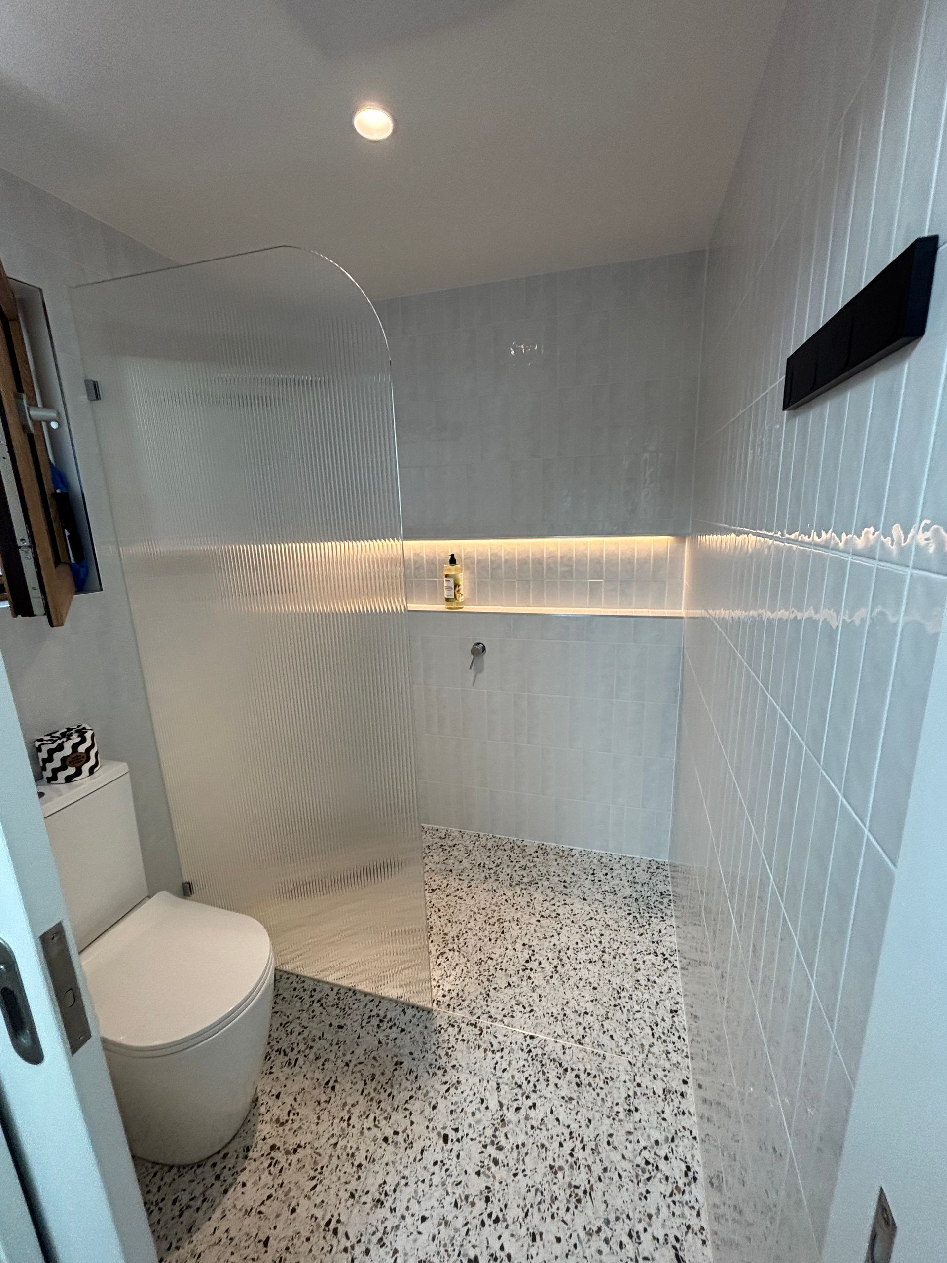 A bathroom with a toilet , sink and shower.