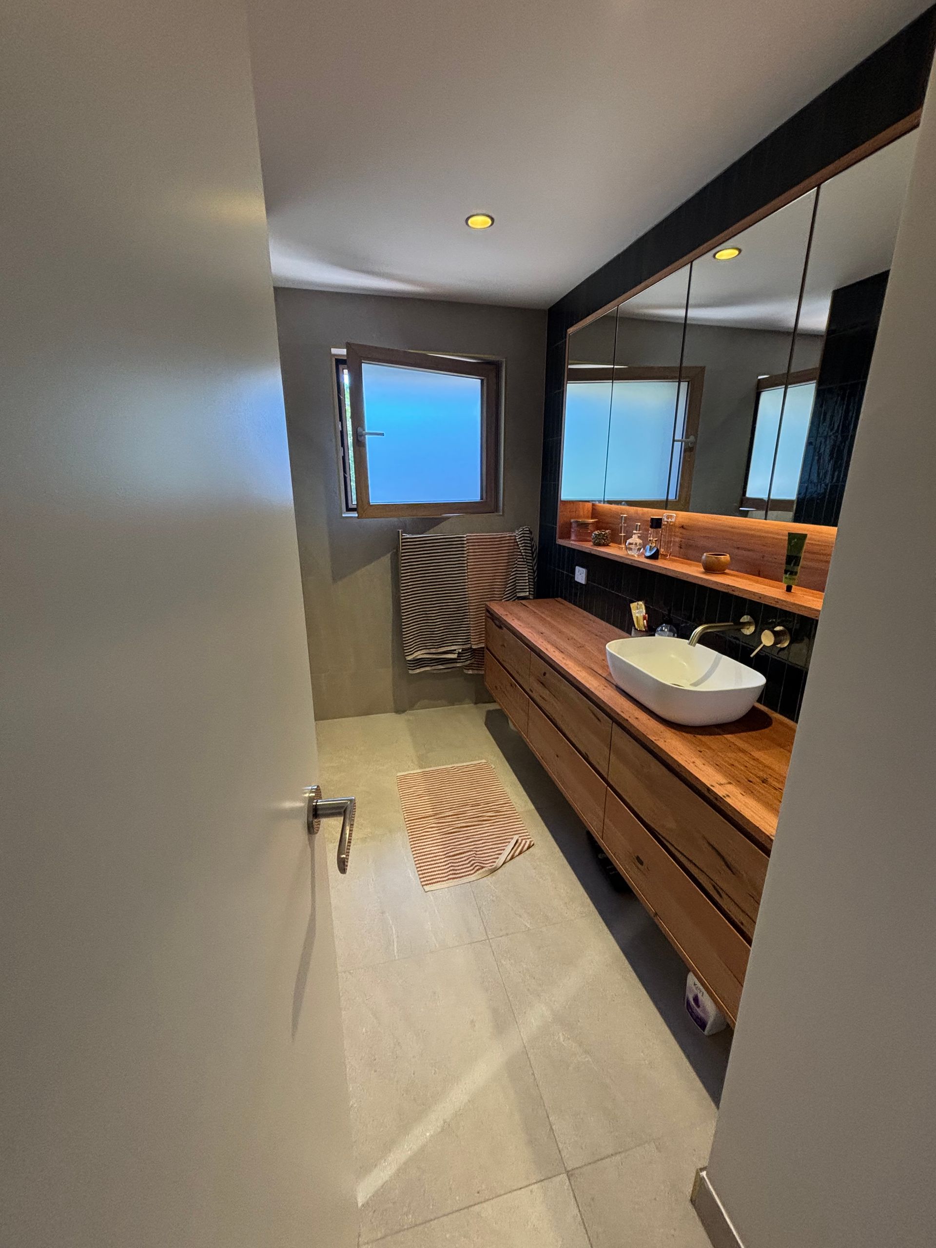 A bathroom with a sink , mirror and window