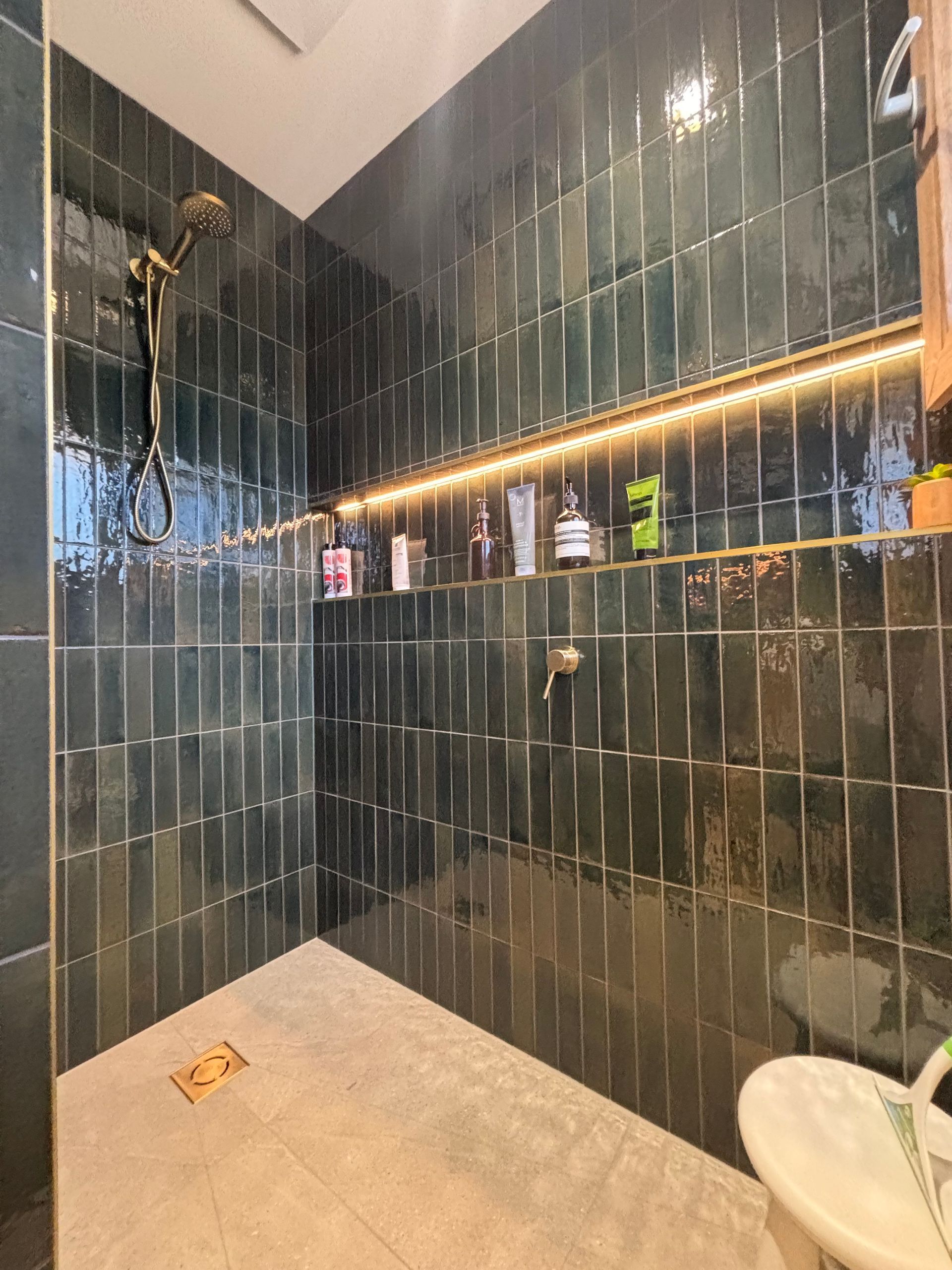 A bathroom with black tiles and a walk in shower.