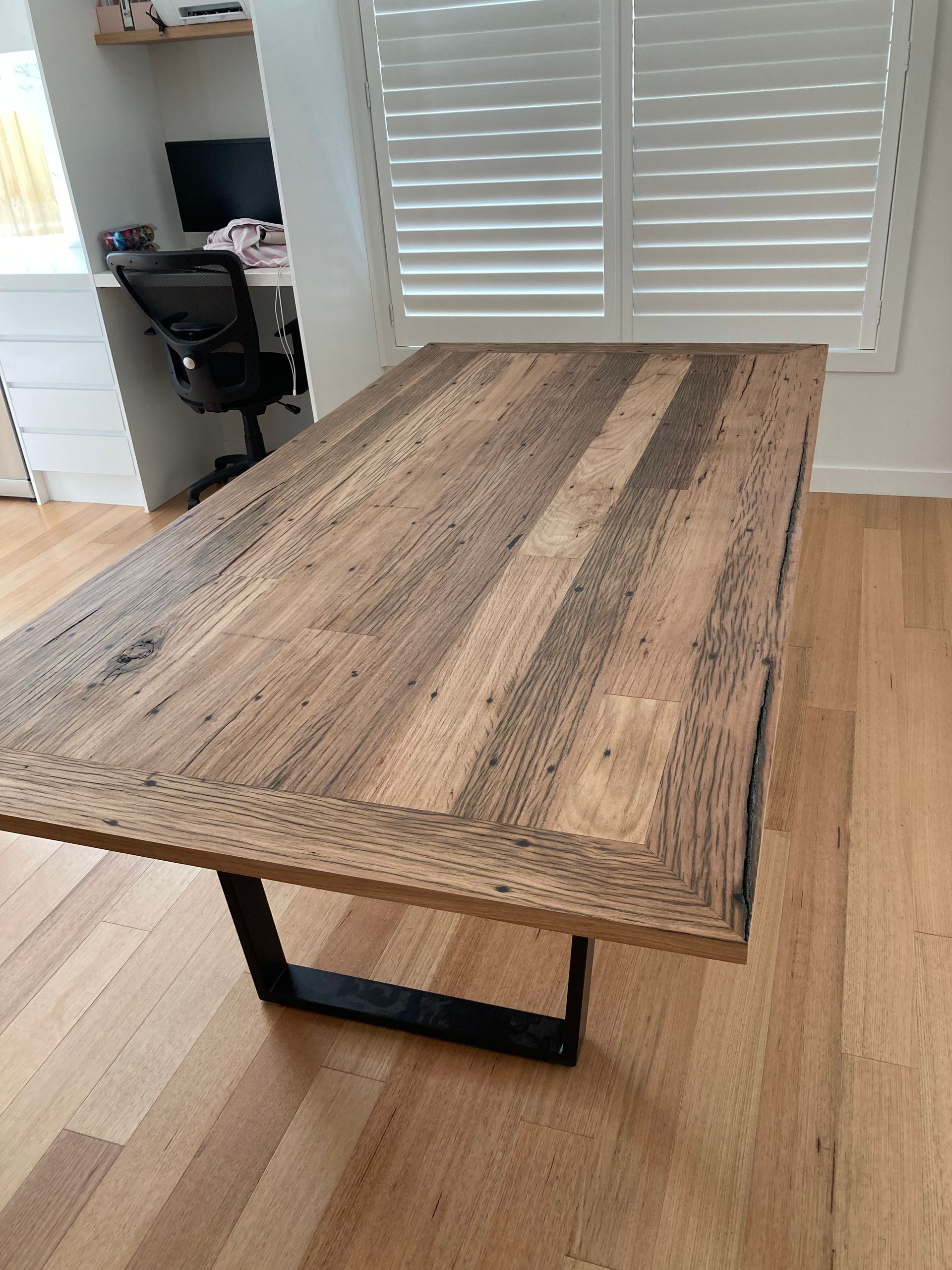A wooden table is sitting on a wooden floor in a room next to a window.