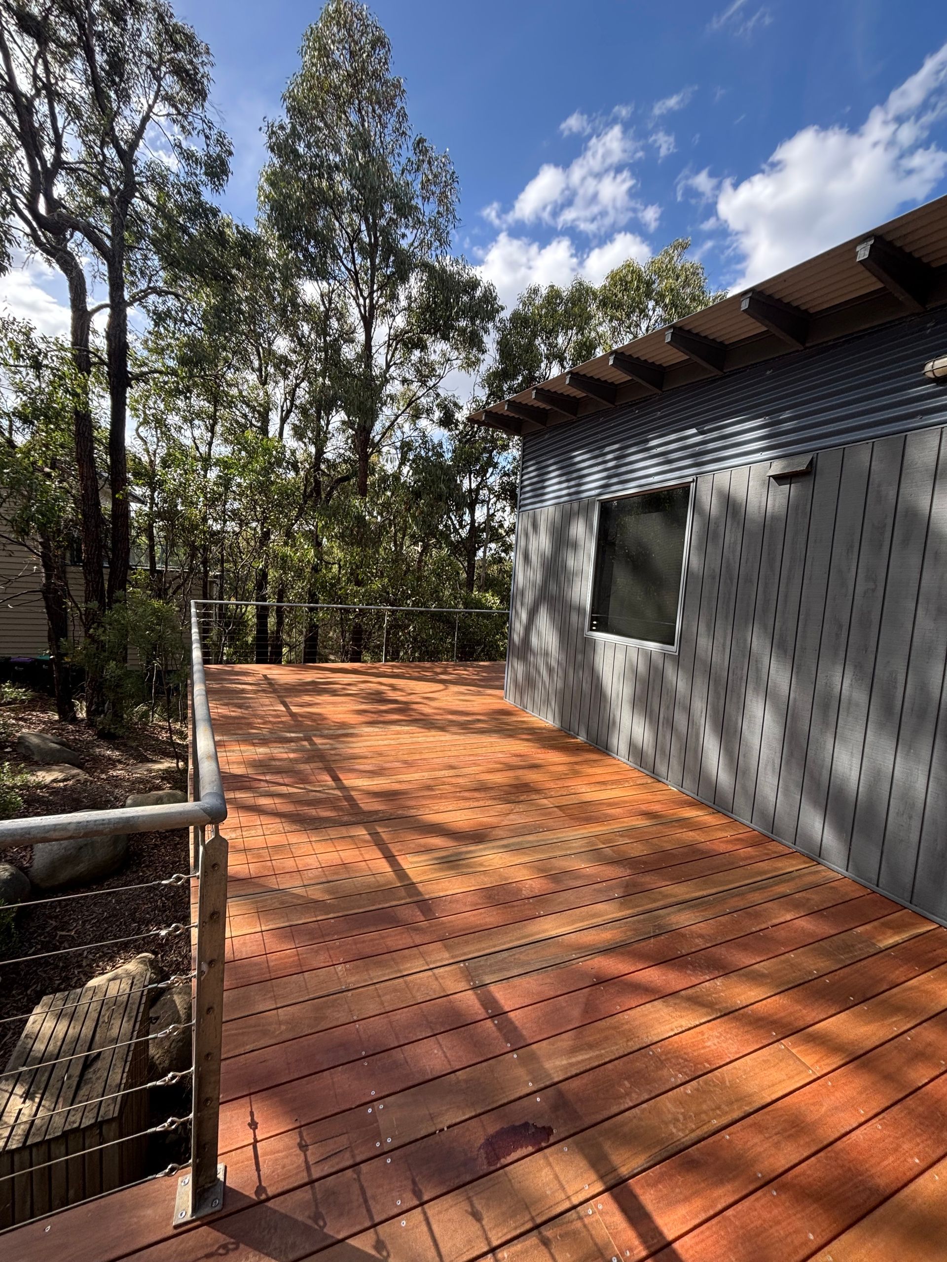 A wooden deck with a hose attached to it in a backyard.
