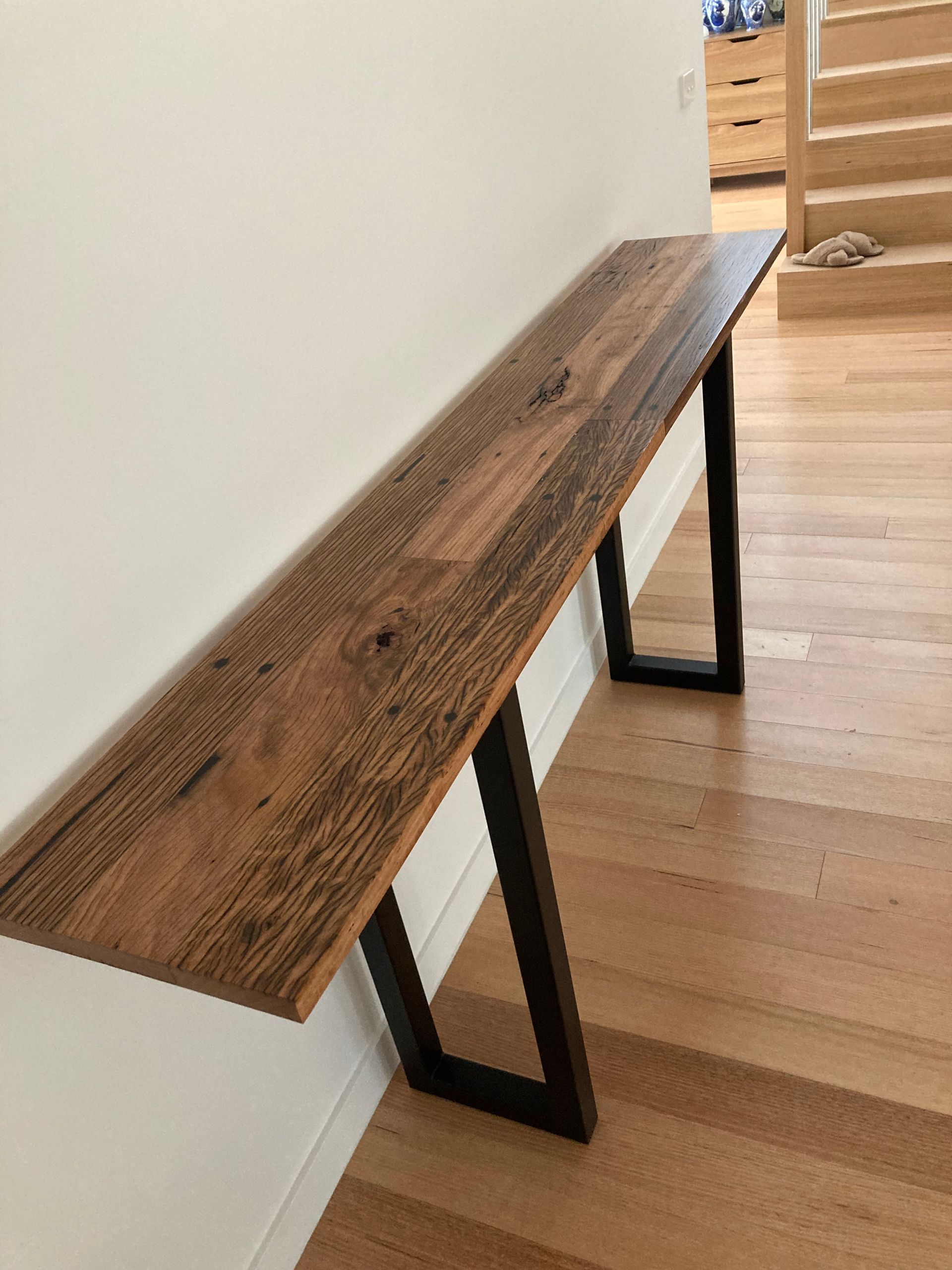 A wooden table with metal legs is sitting on a wooden floor