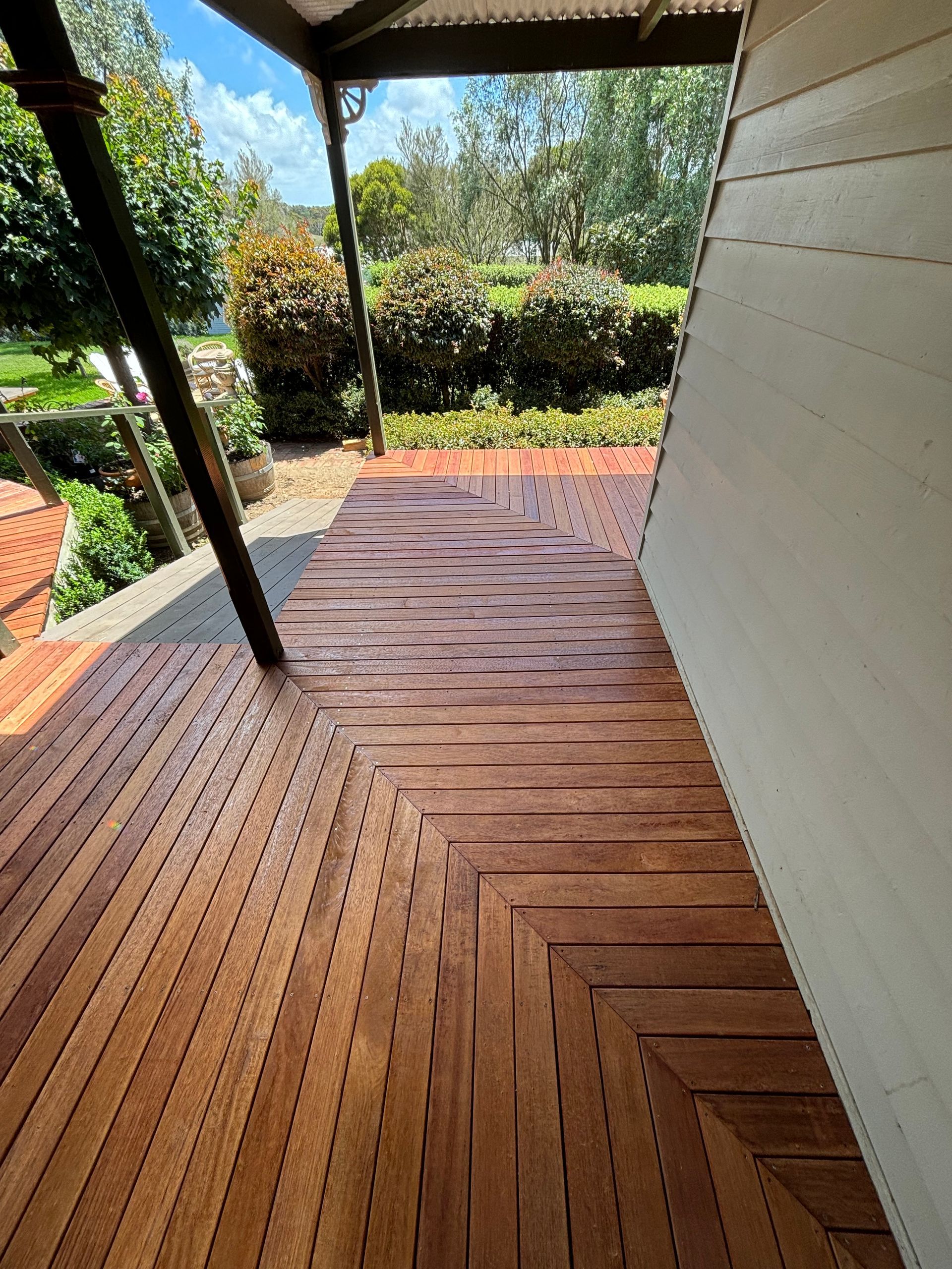 A wooden deck with a view of a garden.
