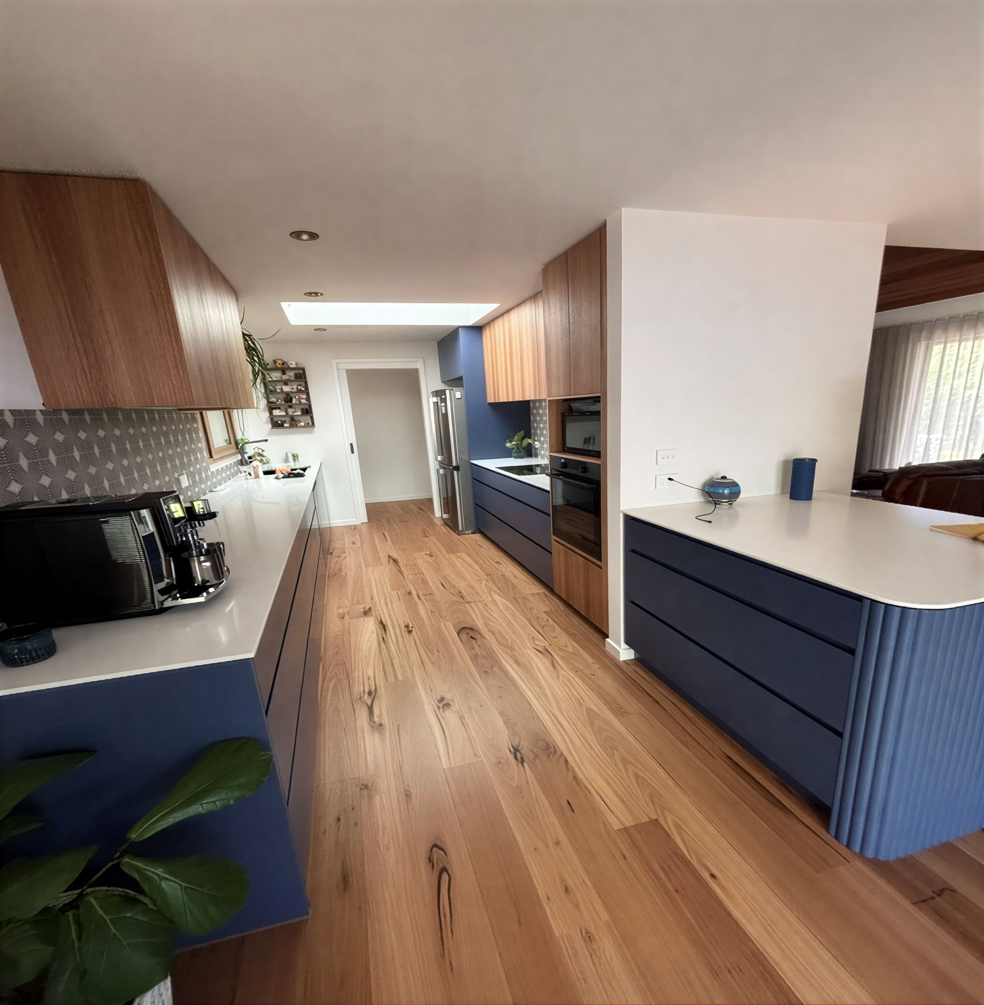 Modern kitchen with blue cabinets, wood countertops, and hardwood floors.