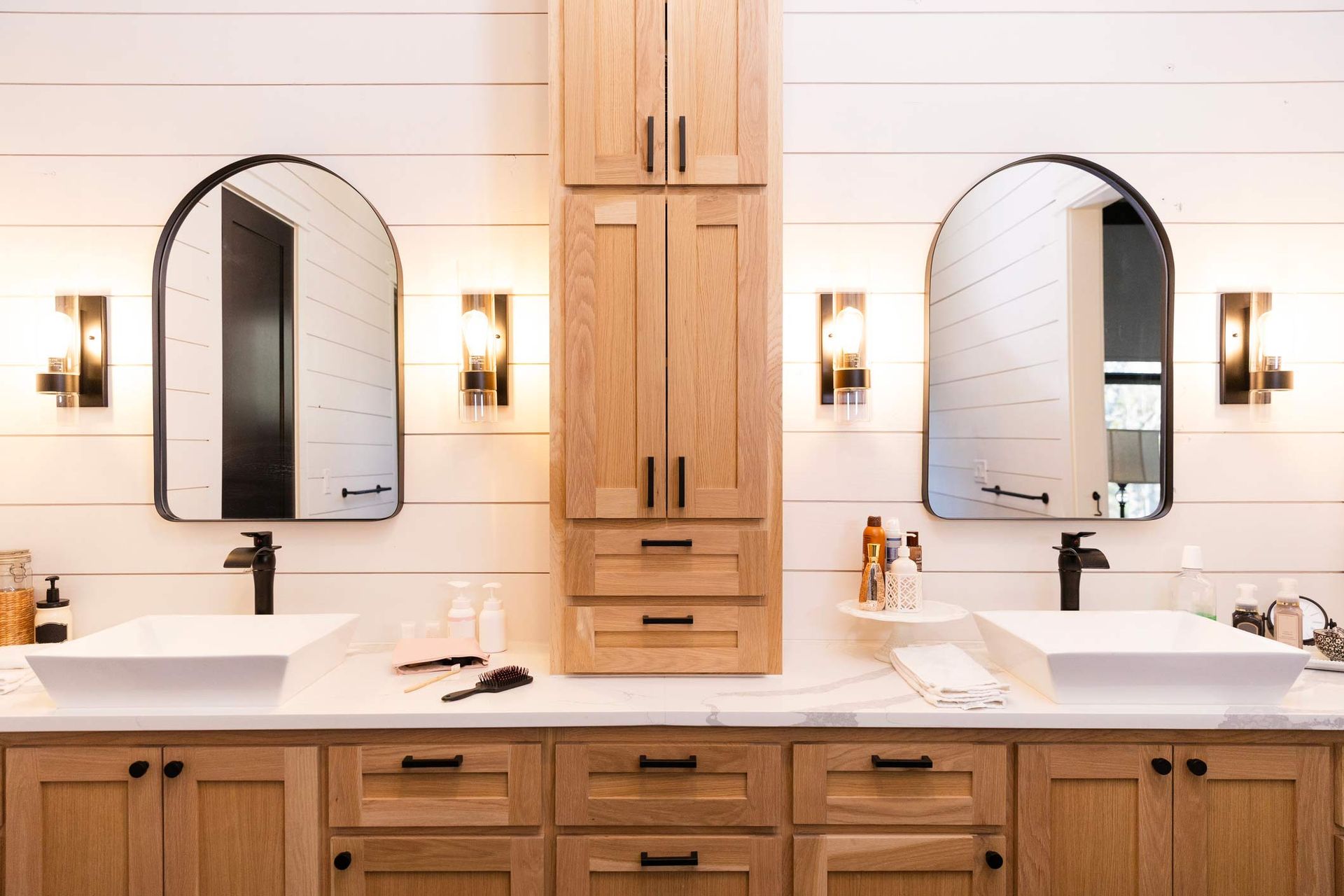 Recently renovated modern bathroom with double sink, natural wood cabinetry, and black hardware