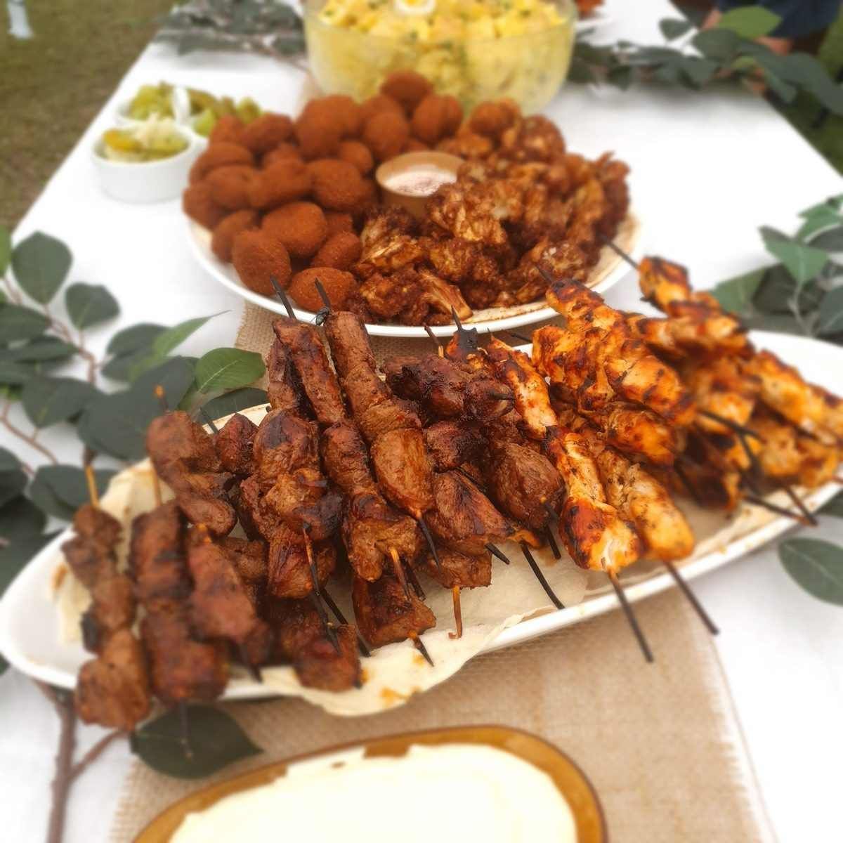 Skewers of grilled meat and chicken on a platter with other dishes at a buffet. - The Habibiz Catering in Wingham NSW