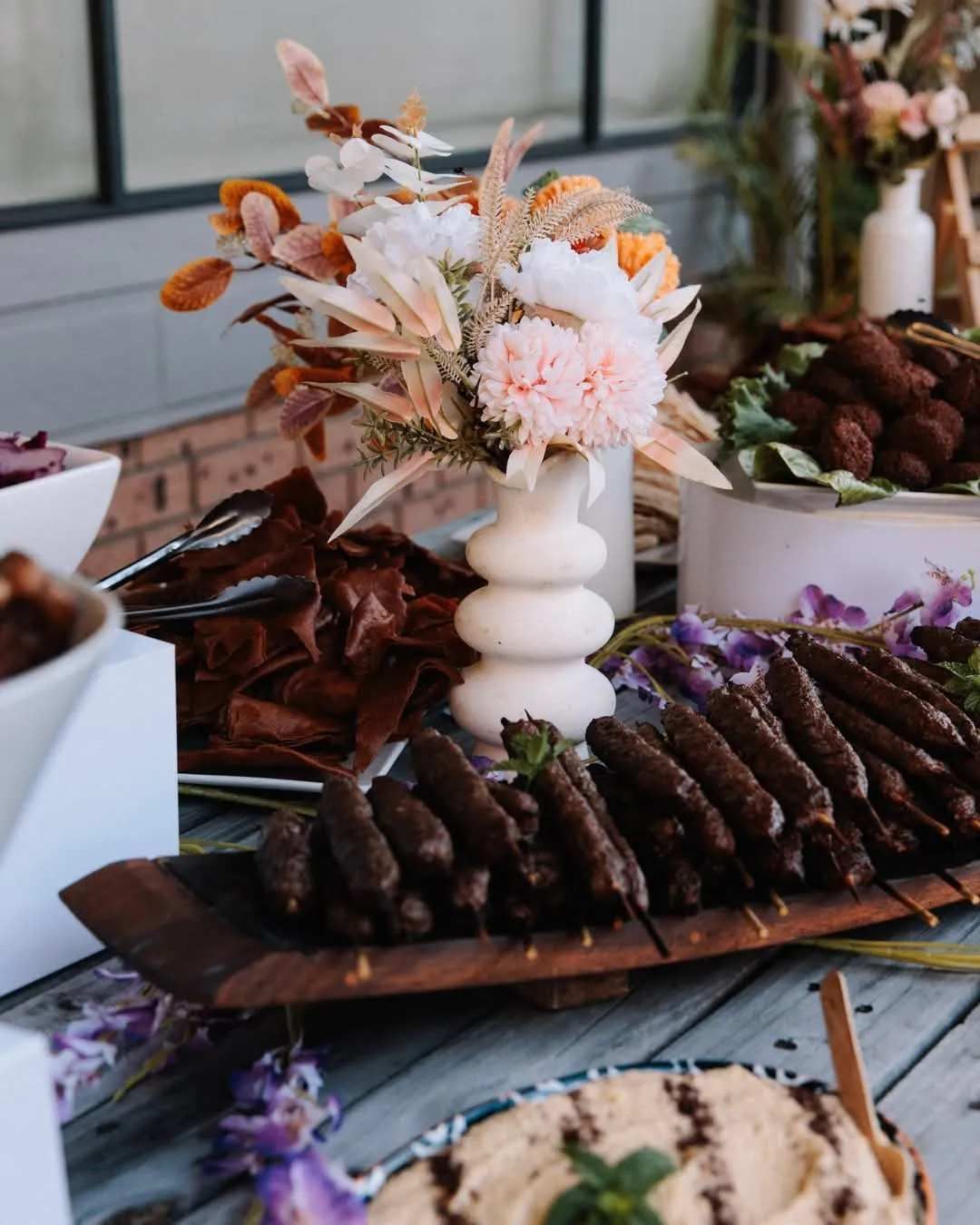 Buffet Table with A Floral Arrangement, Kebabs, Hummus, and Various Appetizers — The Habibiz Catering in the Hunter Valley, NSW