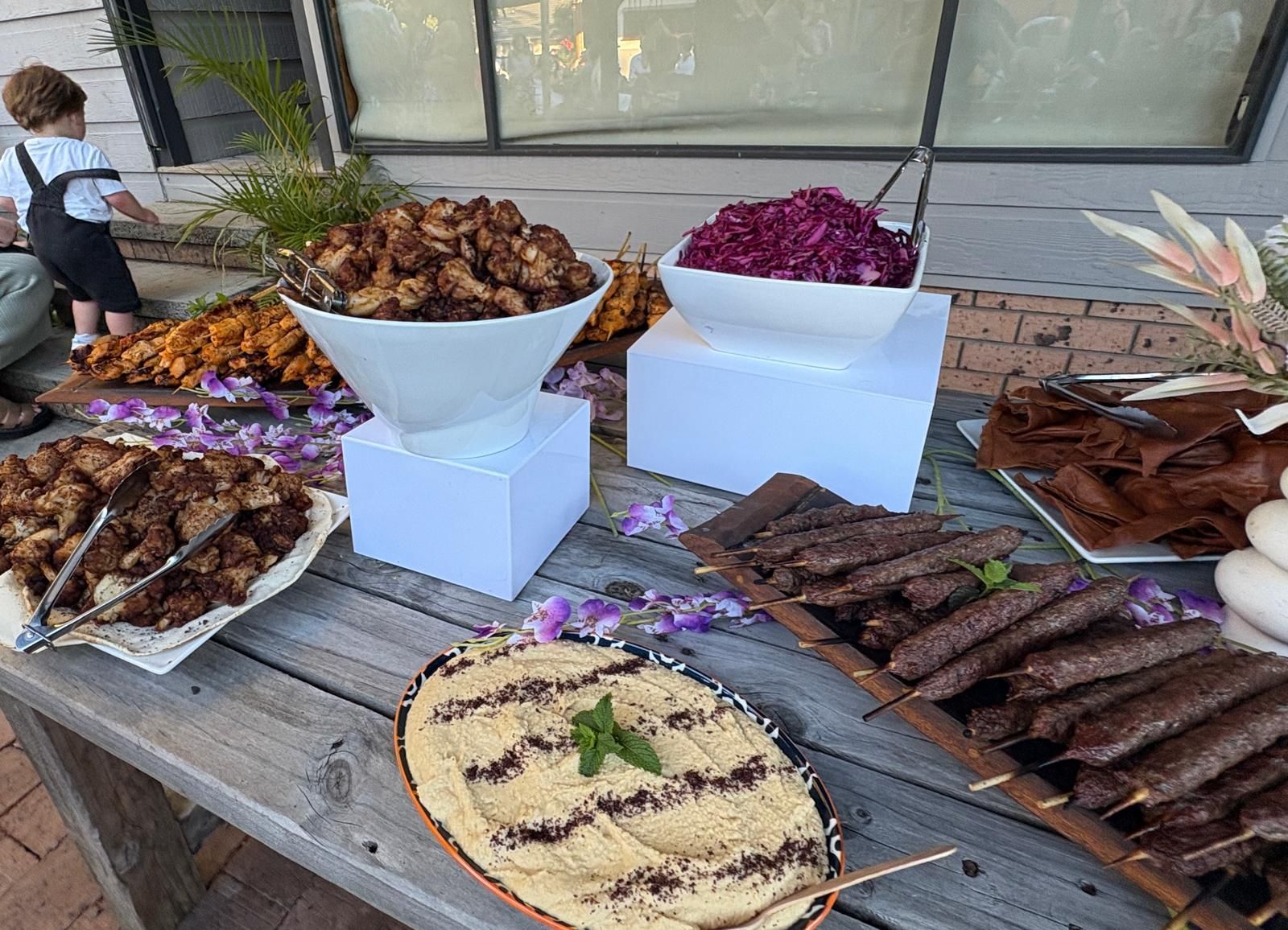 Food buffet on wooden table: cauliflower, red cabbage, hummus and kebabs. — The Habibiz Catering In Wingham, NSW
