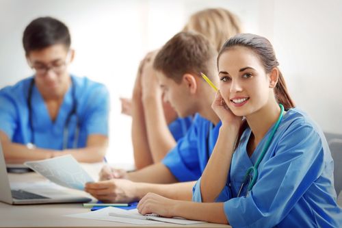 A group of medical students are sitting at a table in a classroom.