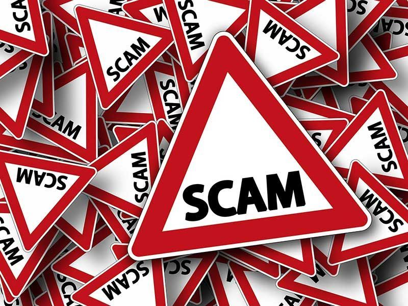 Red warning triangles labeled “SCAM” scattered in a pile on a white background