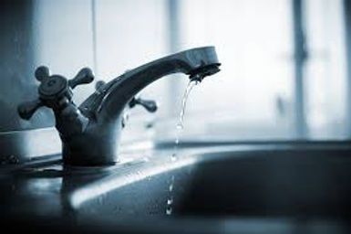 Dripping kitchen faucet over a sink, with water leaking from the spout