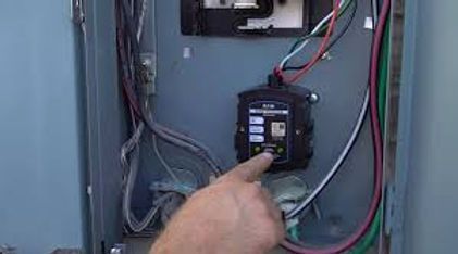 Hands plugging a white cord into a wall outlet beside a windowsill with small tools nearby