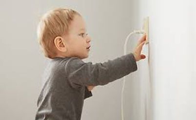 Young child pressing a wall switch on a white wall