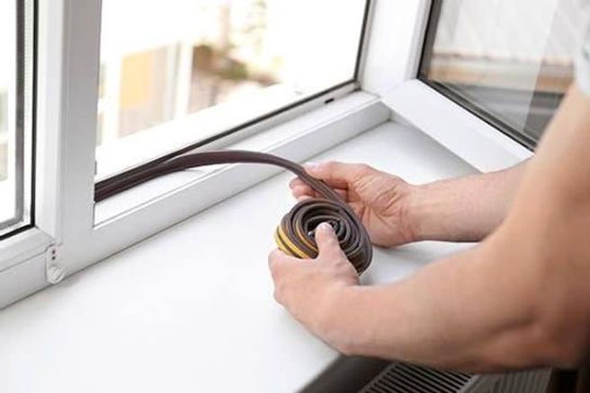Hands coiling cable beside a window sill while installing wiring