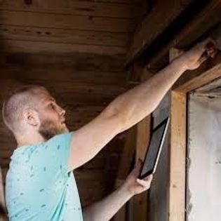 Person using a tablet to inspect or repair a wooden wall indoors