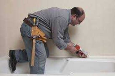 Man caulking a window sill with a caulk gun beside a white window frame