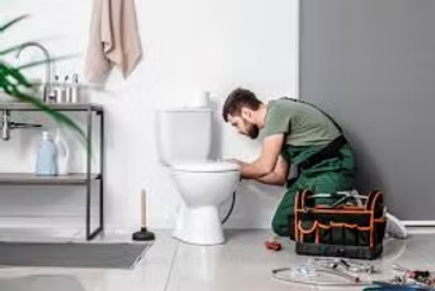 Plumber kneeling beside a toilet, using tools in a bathroom during repair work