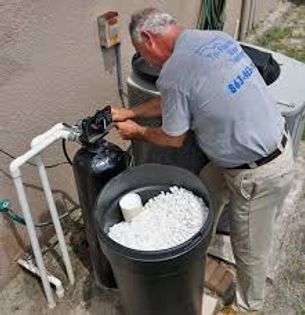 Man adjusting pool equipment beside a black cooler filled with ice outdoors.