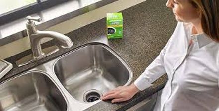 Person inspects a stainless steel kitchen sink near a faucet and drain