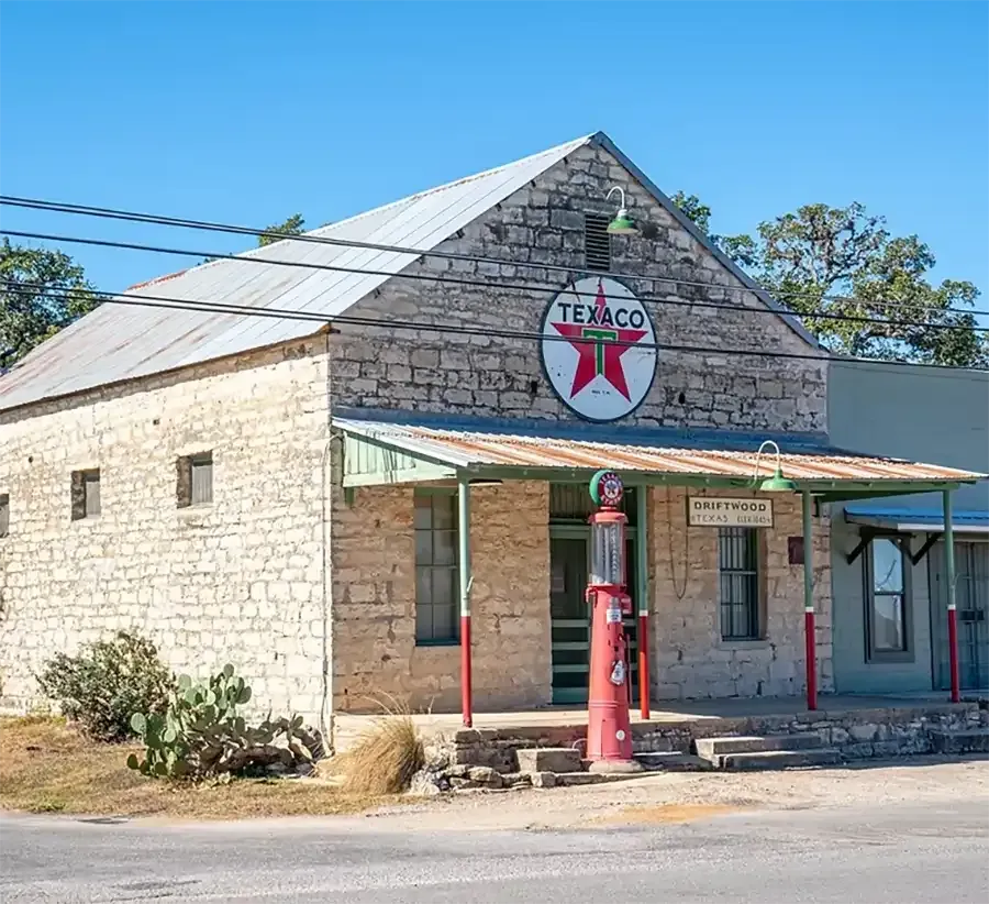 Old Texaco gas station with stone facade, red vintage pump, and weathered awning under a clear blue sky