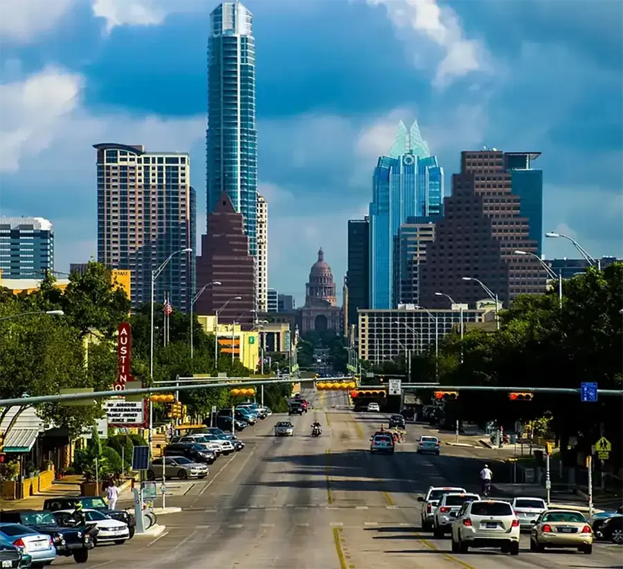 Downtown city skyline with tall modern skyscrapers above a busy multilane street under clear blue sky