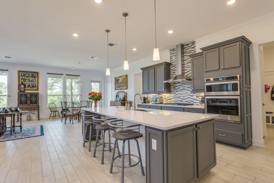 Bright modern kitchen with gray cabinets, large island, bar stools, and pendant lights