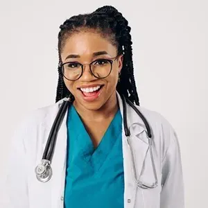 Smiling doctor in white coat and teal scrubs with a stethoscope against a light background