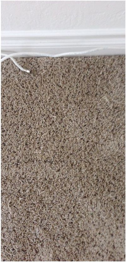 A close up of a brown carpet with a white trim.