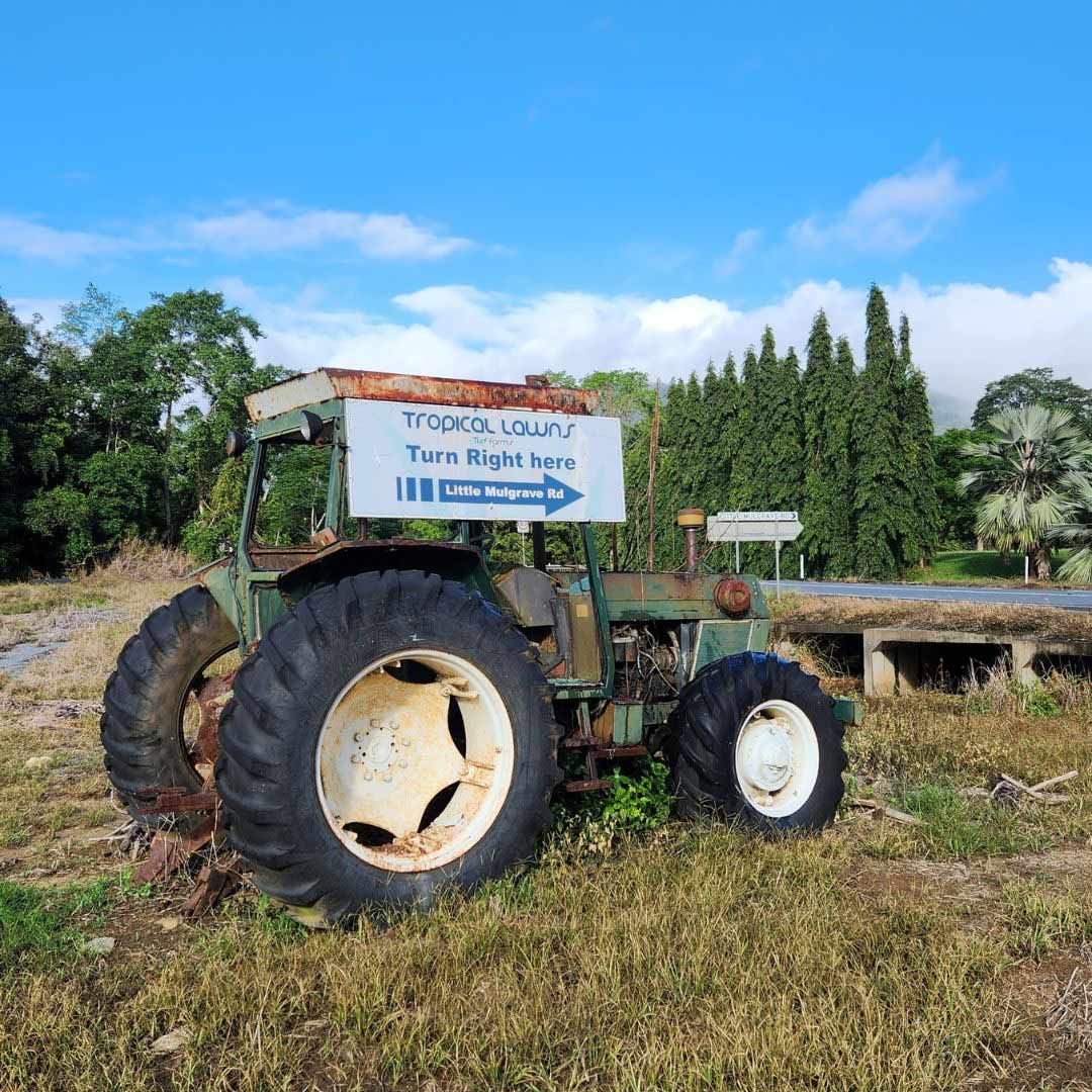 An Old Tractor Is Parked In A Field With A Sign Above It That Says Turn Right Here — Tropical Lawns Pty Ltd In Little Mulgrave Qld
