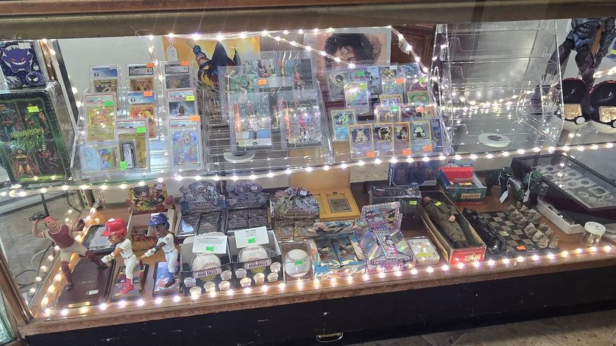 A lit display case filled with small figurines, toys, and collectibles on shelves and trays