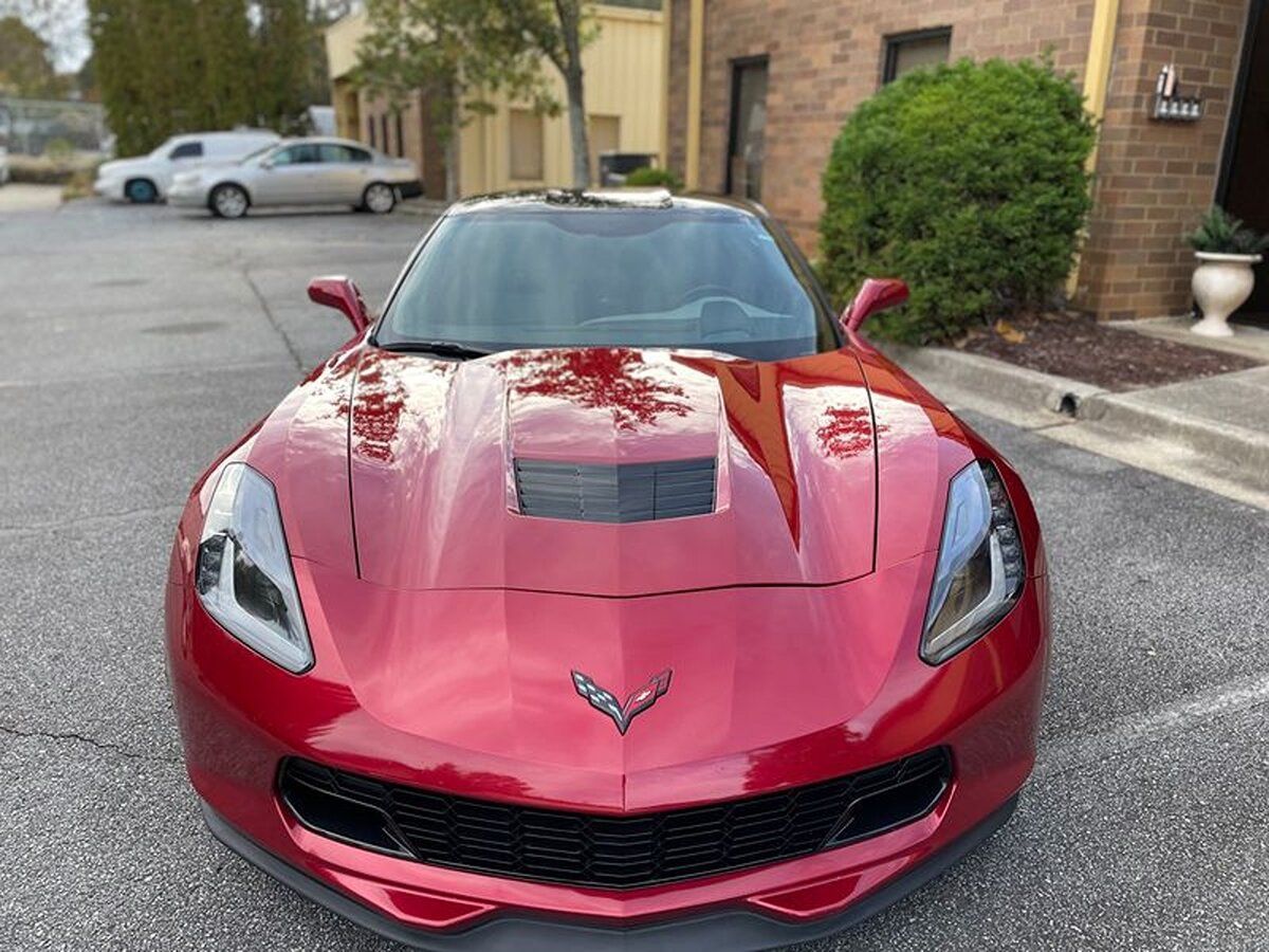 A red corvette is parked in a parking lot in front of a building.