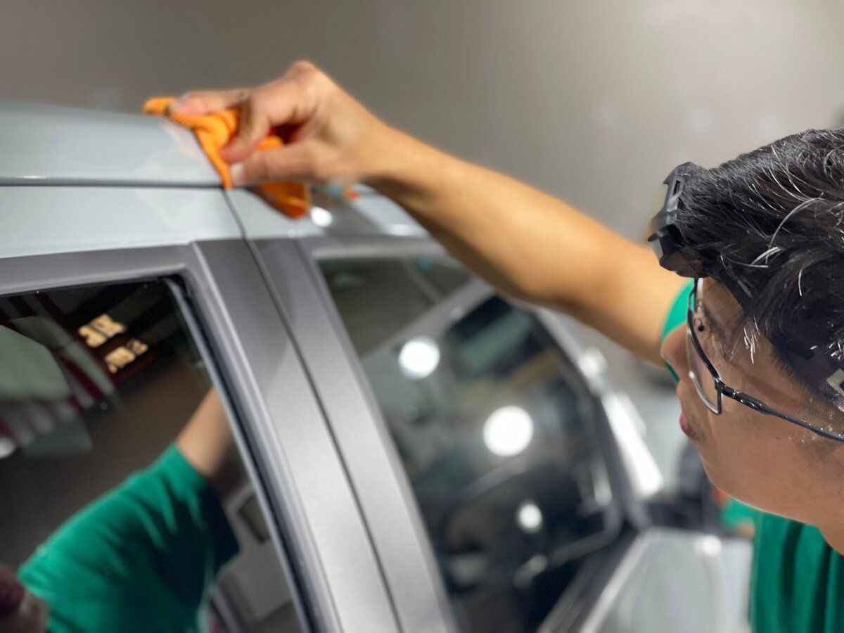 A man is cleaning a car with an orange cloth