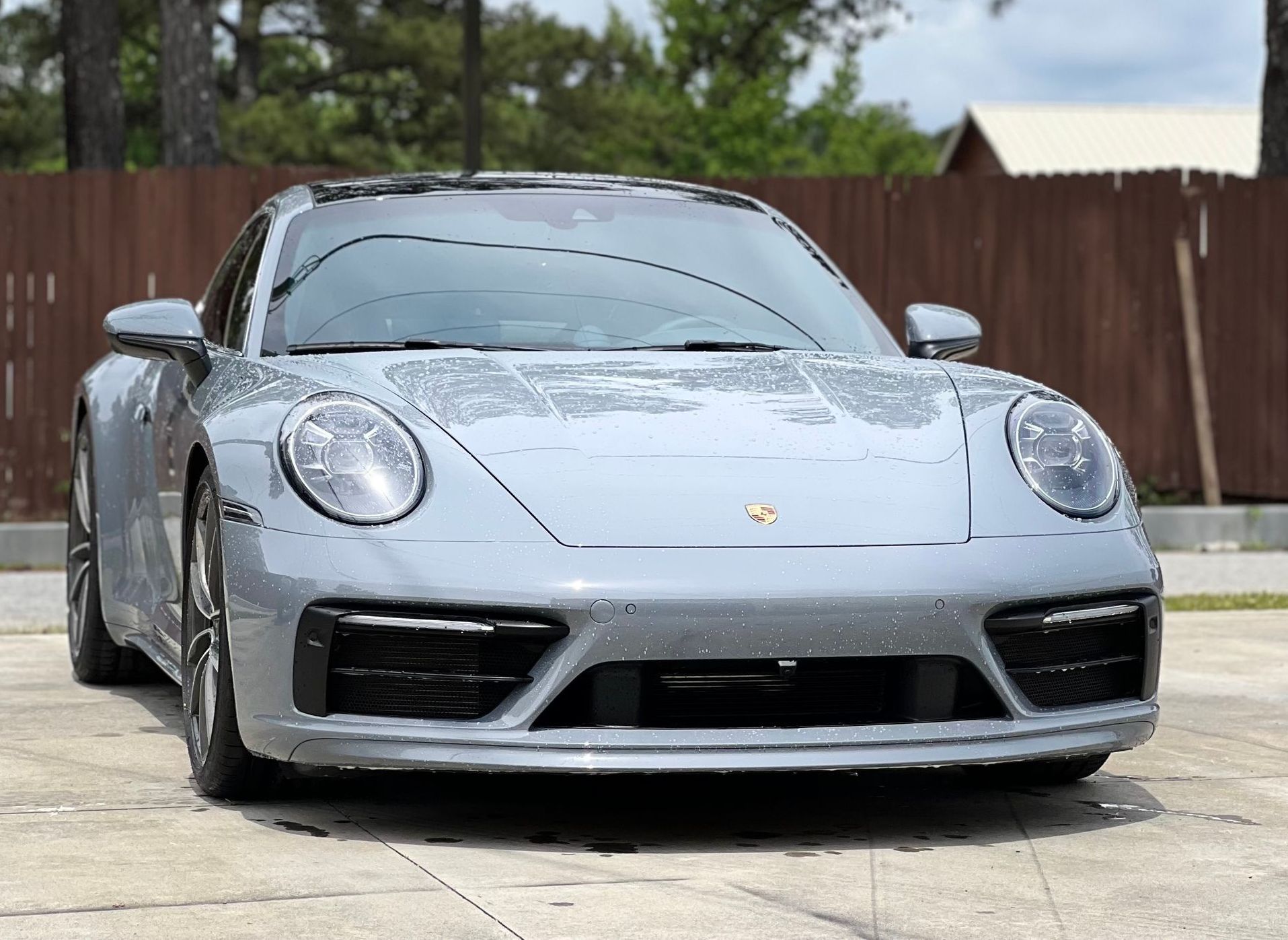 A gray porsche 911 is parked in a parking lot.