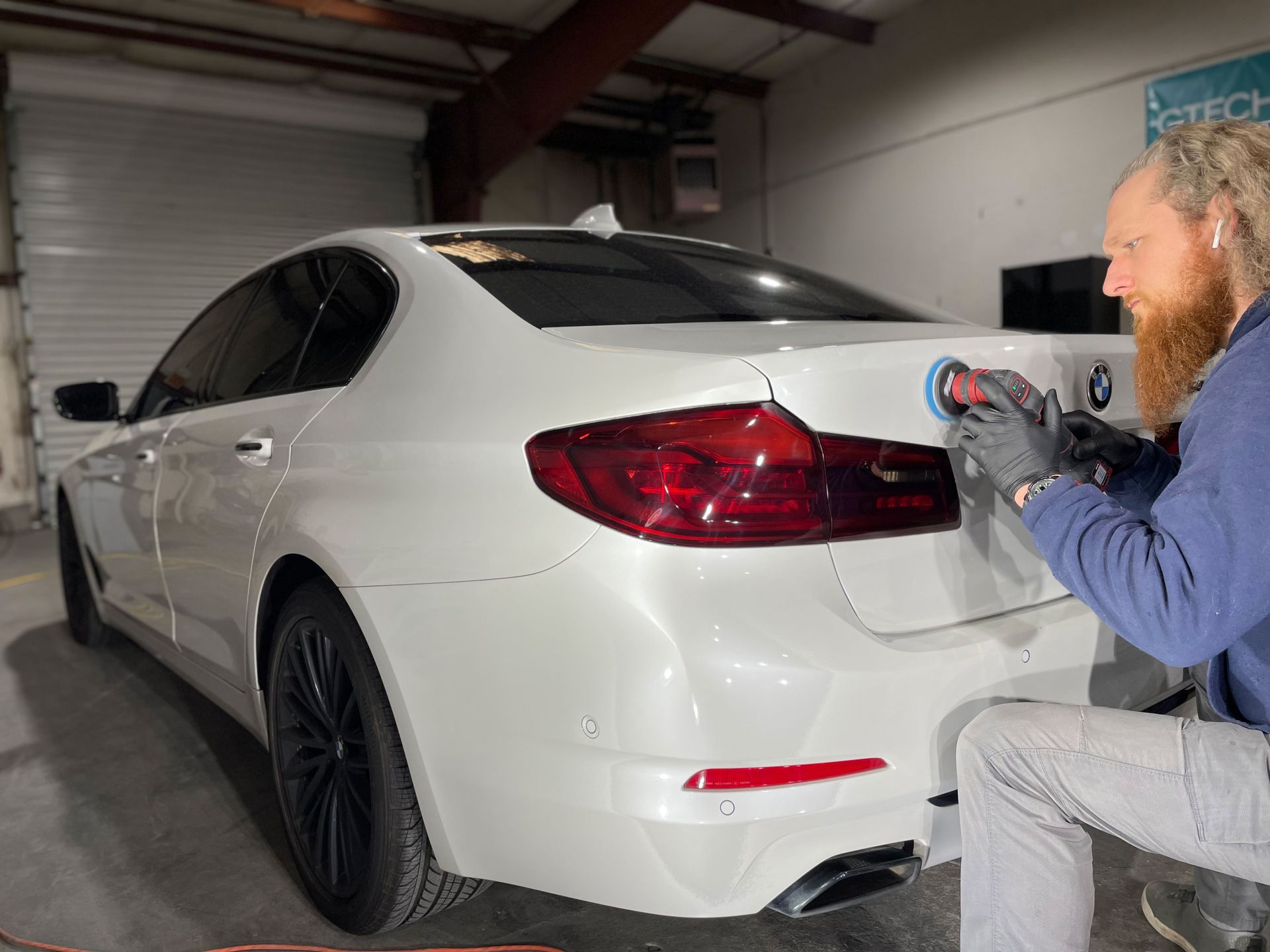 A man is polishing a white car in a garage.
