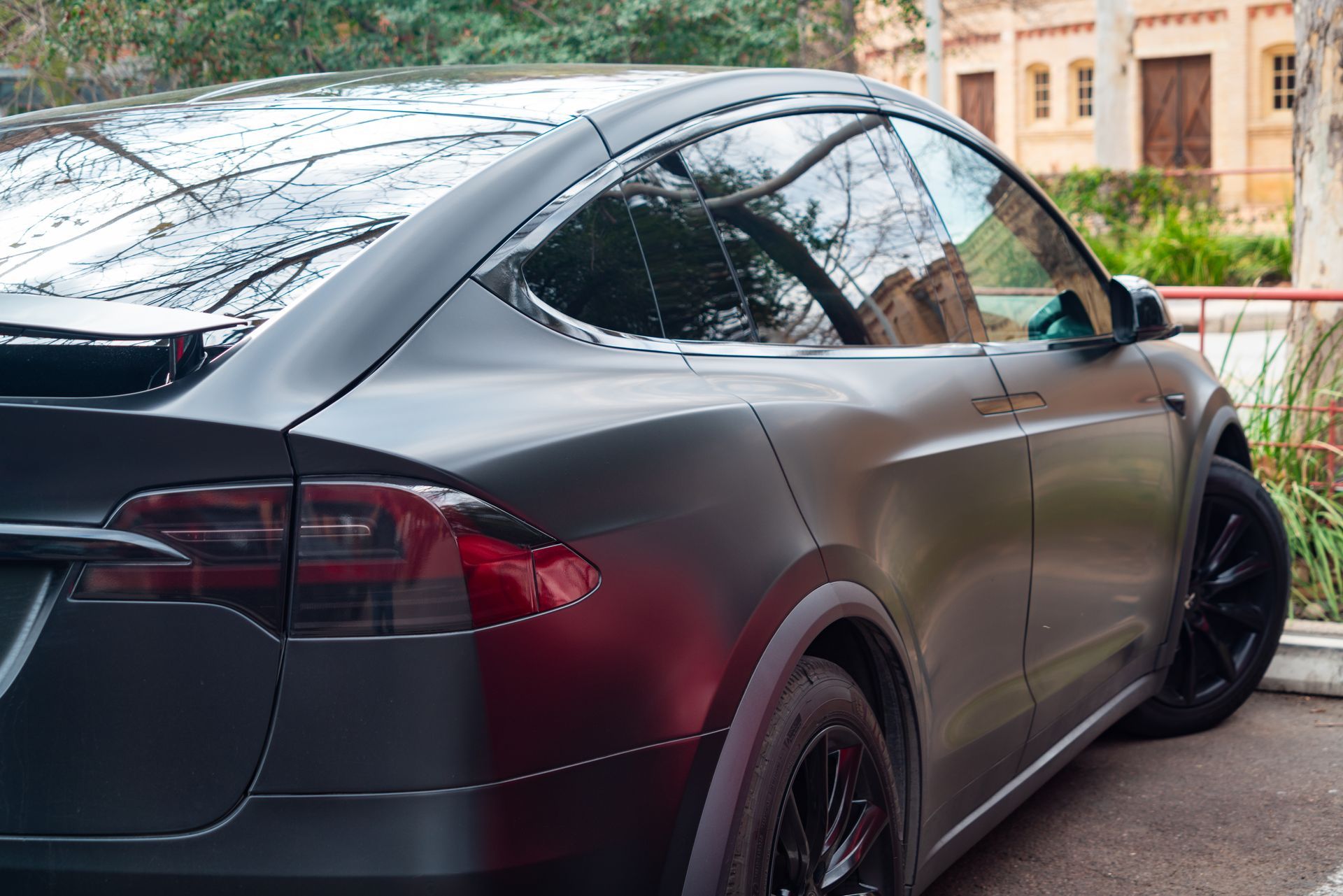 Black Tesla SUV parked outside a building, tinted windows, black wheels.