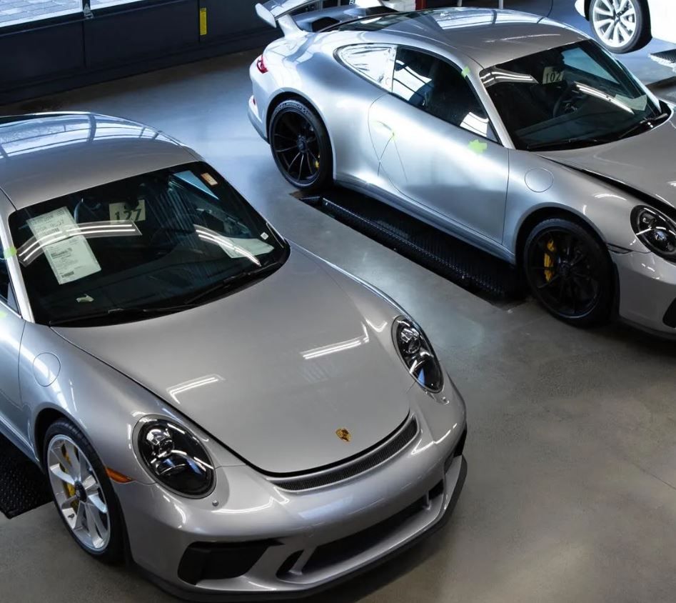 Two silver cars are parked next to each other in a garage