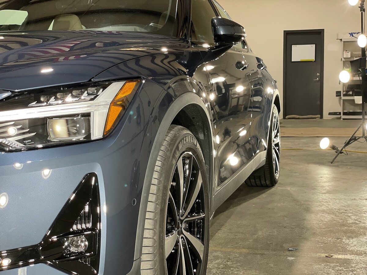 A blue car is parked in a garage next to a door.