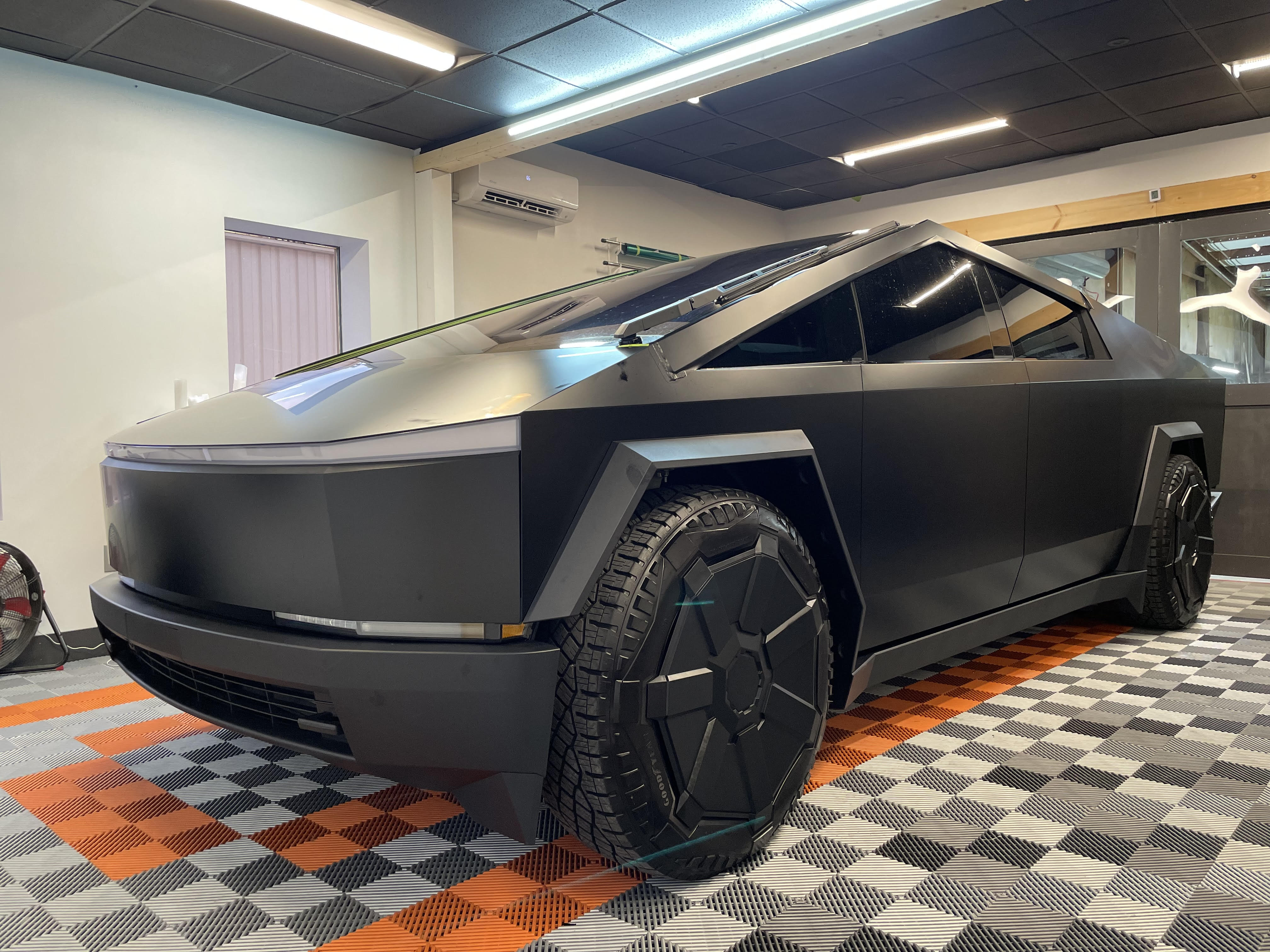 A black tesla cybertruck is parked in a garage.