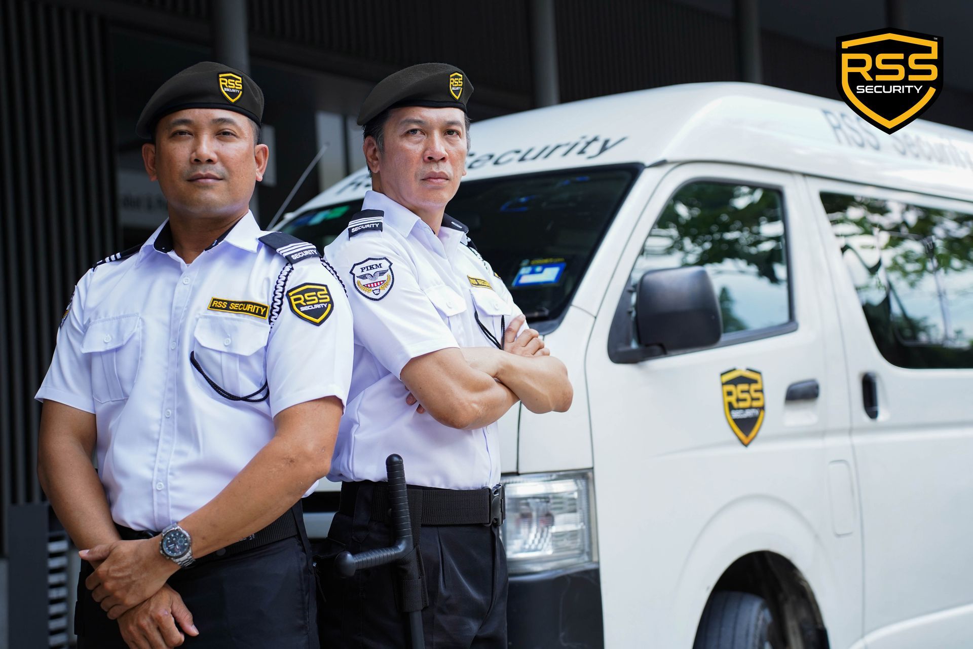 Two security officers in uniform stand in front of a white security van marked with the RSS Security logo.