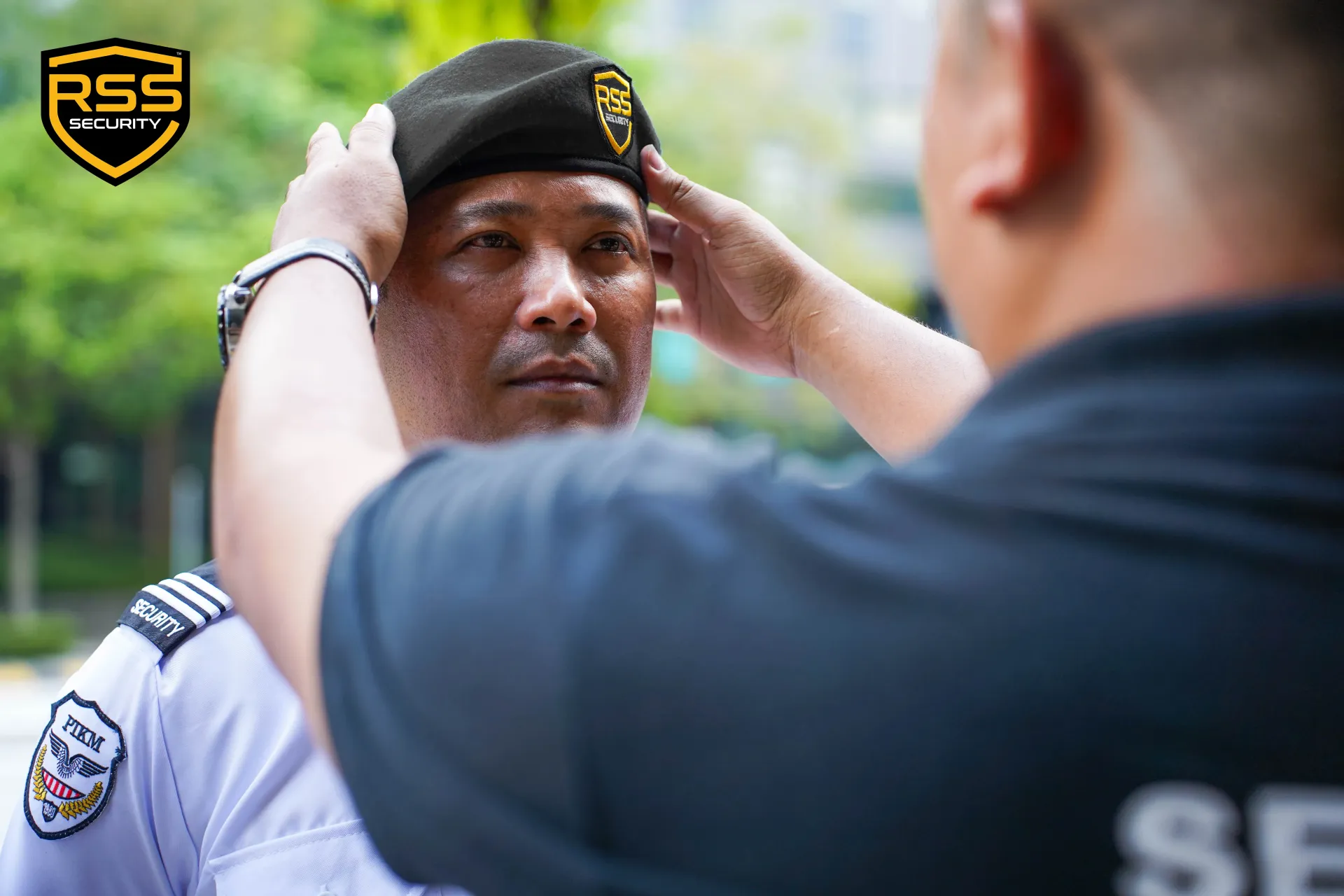 Security guard adjusting another guard’s beret outdoors