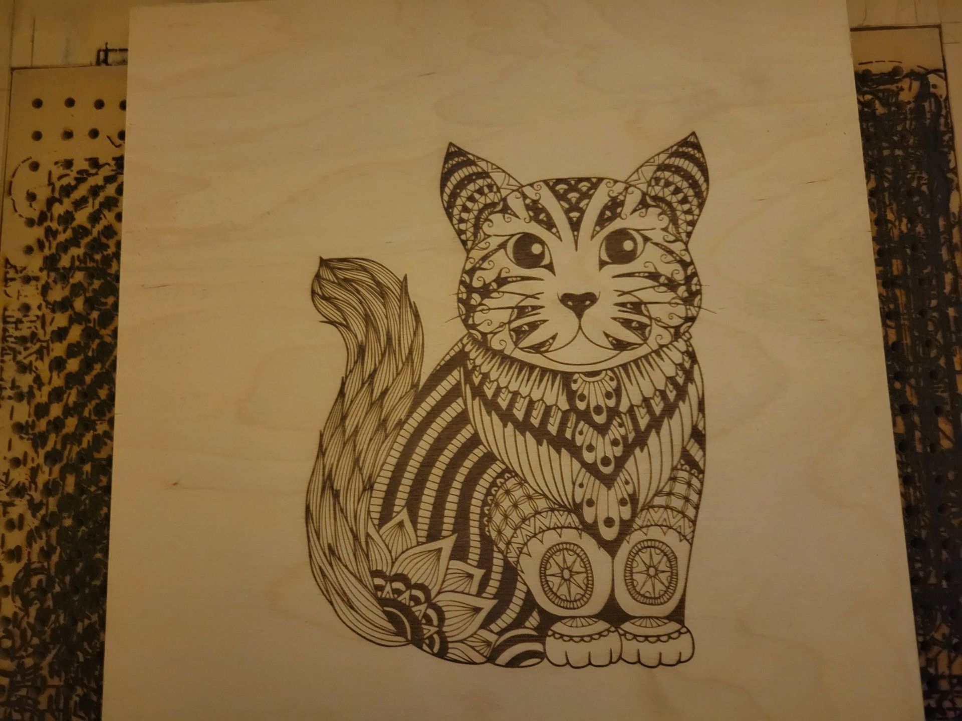 Laser-etched ornate cat on wood panel.