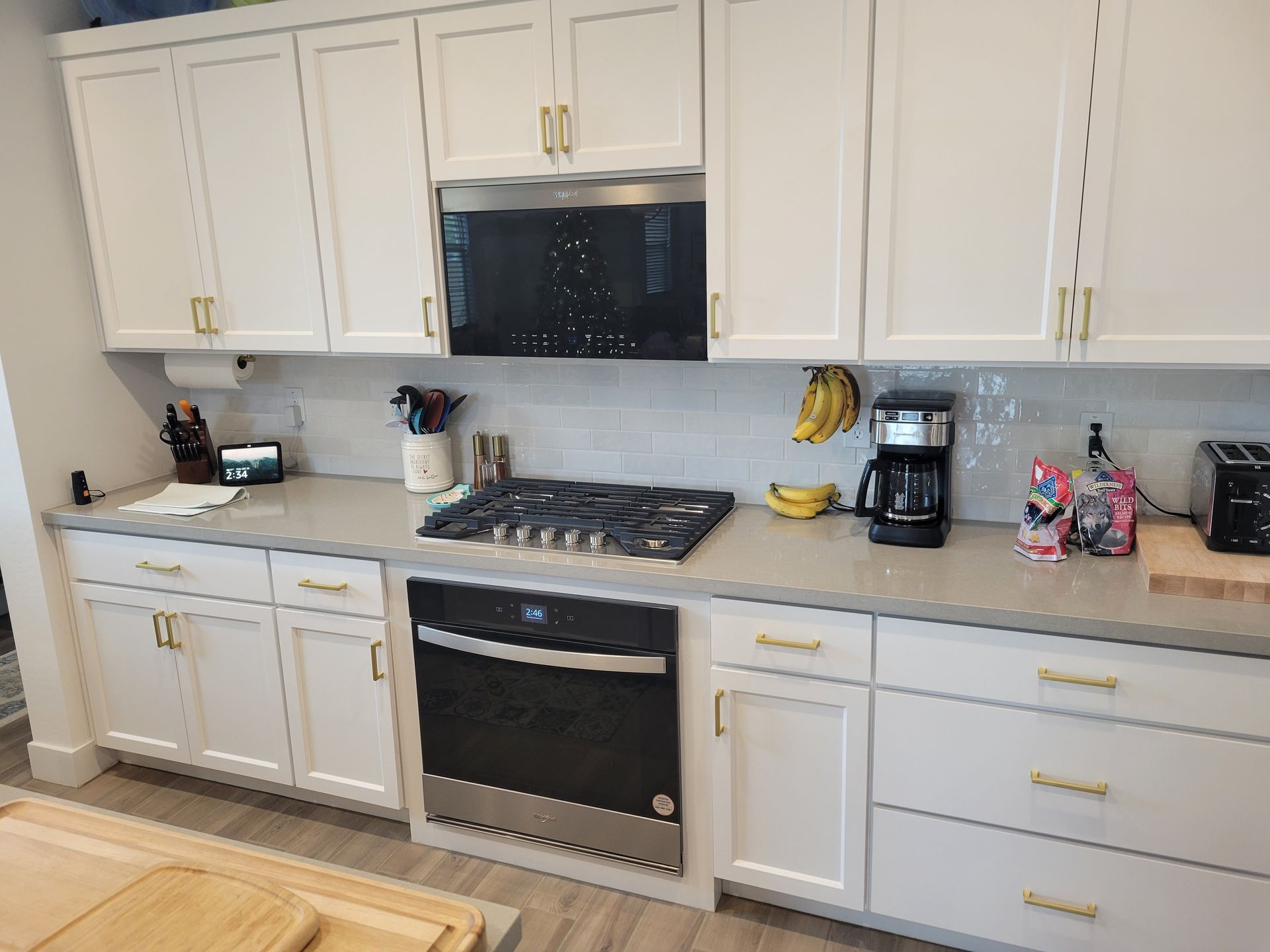 White kitchen with stainless steel appliances, gray countertops, and white cabinets.