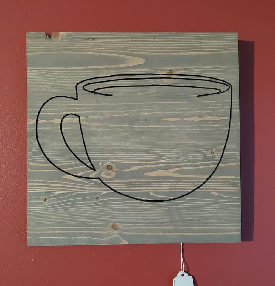 Wooden square with gray stain, black outline of coffee cup.
