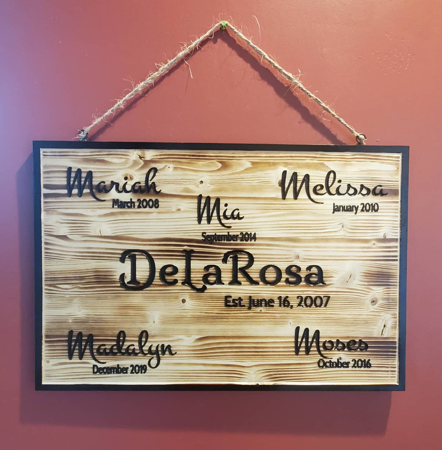 Wooden sign with family names: Mariah, Mia, Melissa, Madalyn, and Mobes, with birthdates and