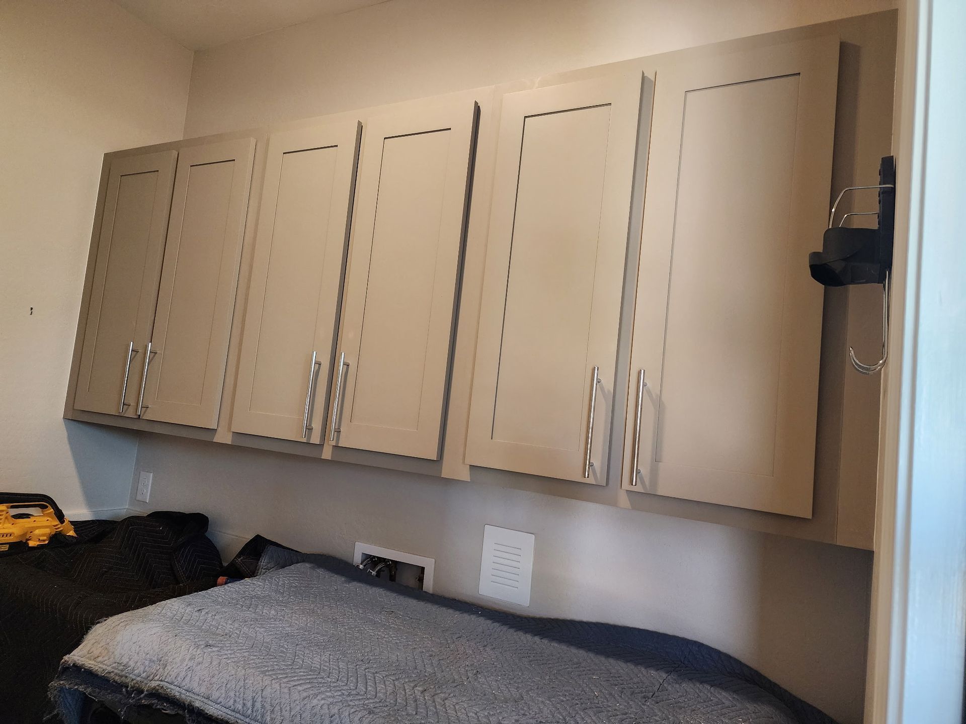 Light-colored cabinets mounted on a wall, with a cluttered area below.