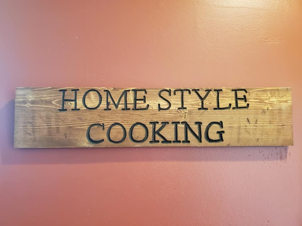 Wooden sign on a red wall with engraved text: